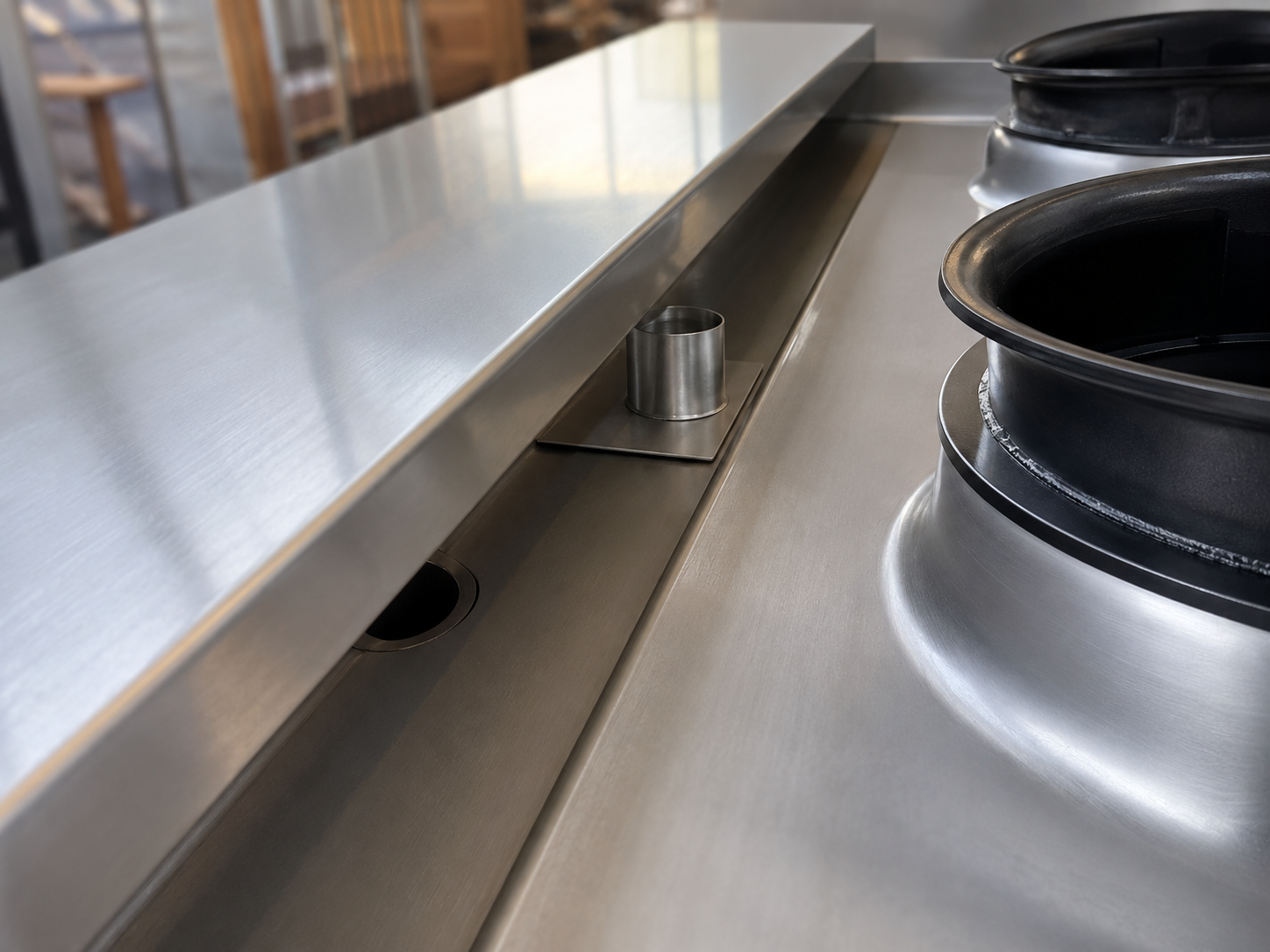 Water flowing into a circular integrated wok range drain