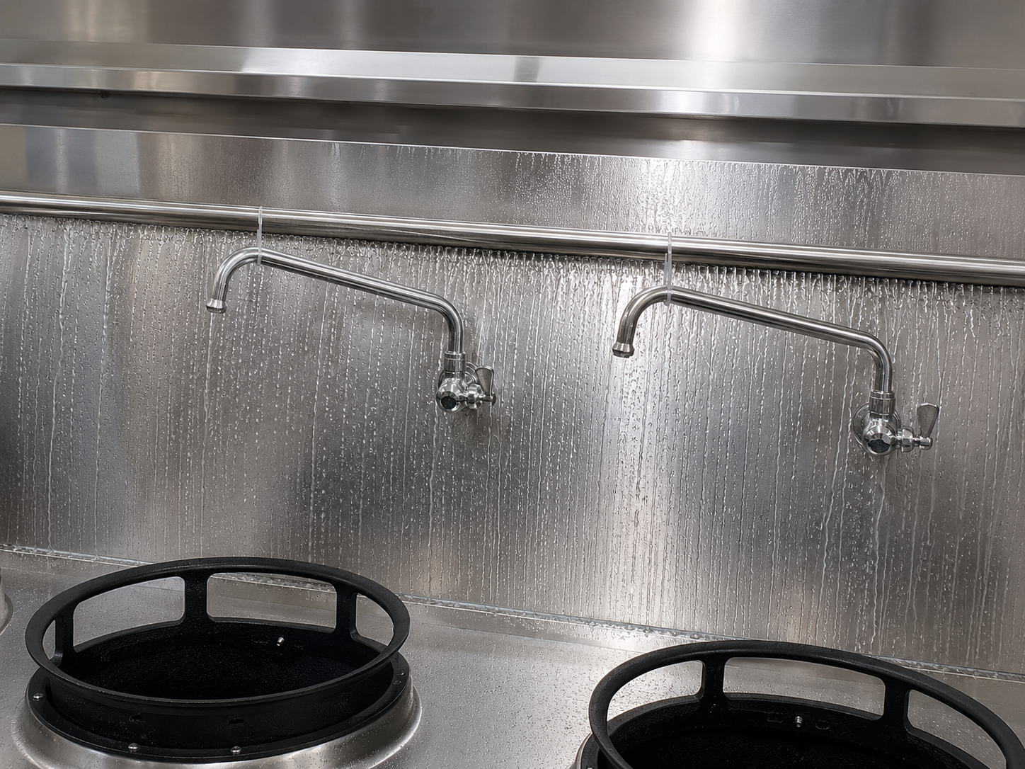 Water flowing down the stainless wok range backboard